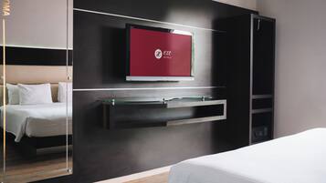Una habitación de hotel moderna con una cama, un televisor montado en la pared y un armario.