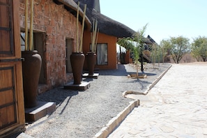 A building with a brick exterior and a thatched roof. There are large vases placed outside the building.
