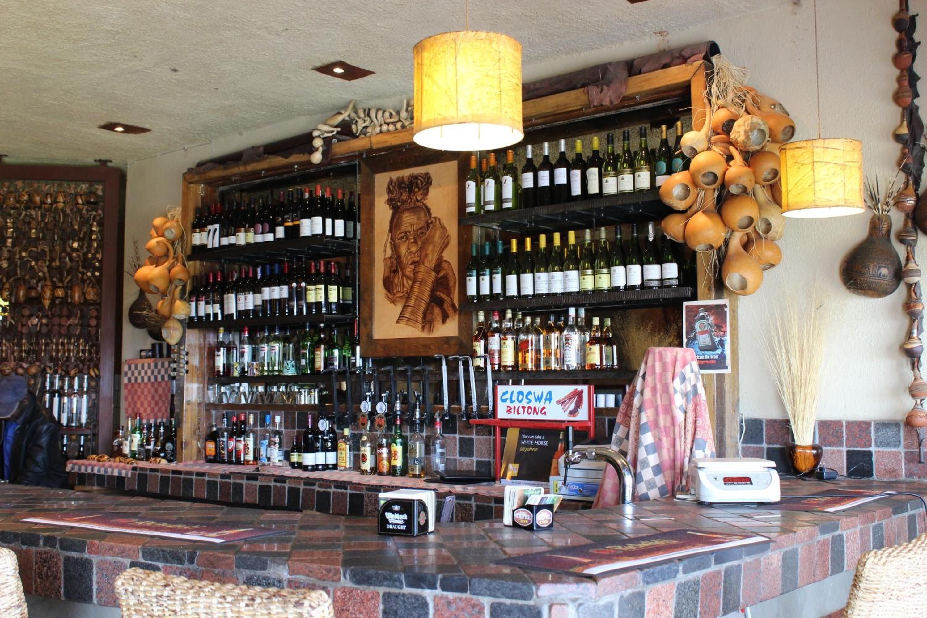 A bar area with a stone counter, shelves of wine bottles, and a sign reading "CLOSWA BILDTONG".