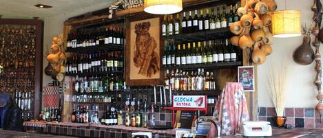 A bar area with a stone counter, shelves of wine bottles, and a sign reading "CLOSWA BILDTONG".