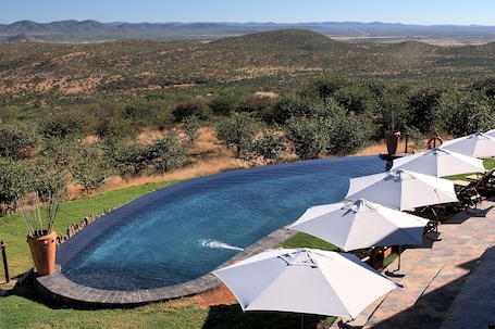 Outdoor pool, pool umbrellas, sun loungers. Opuwo Country Hotel