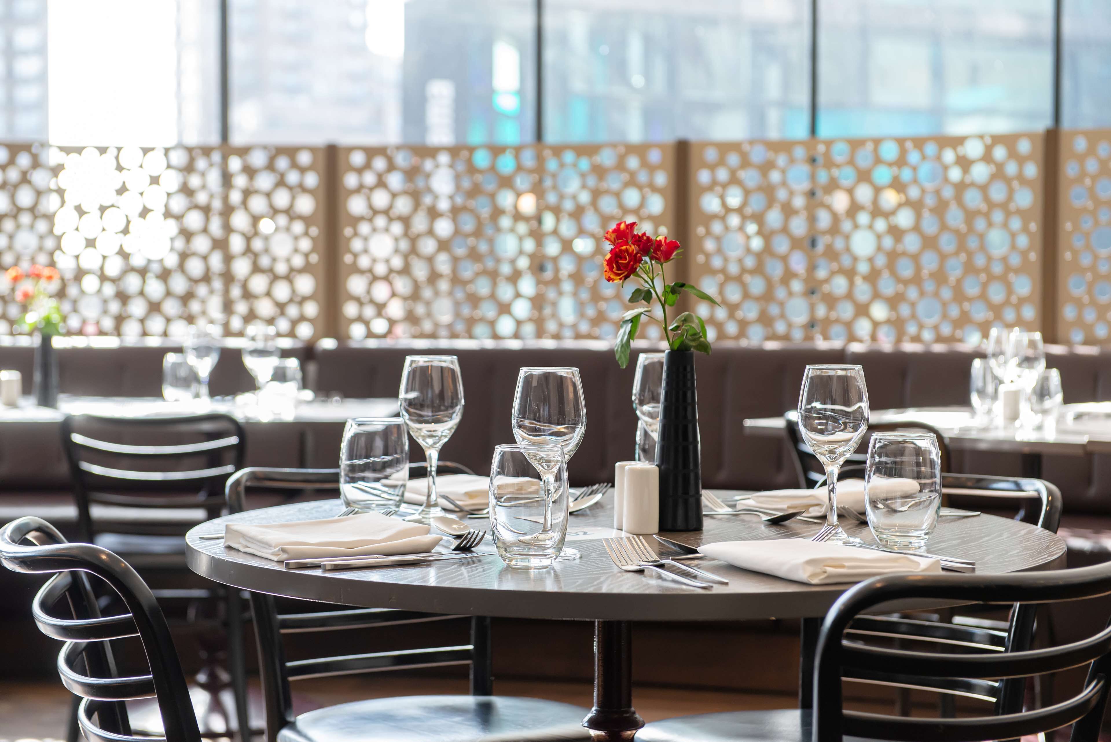 A dining area with round tables, chairs, and a decorative wall with circular patterns.
