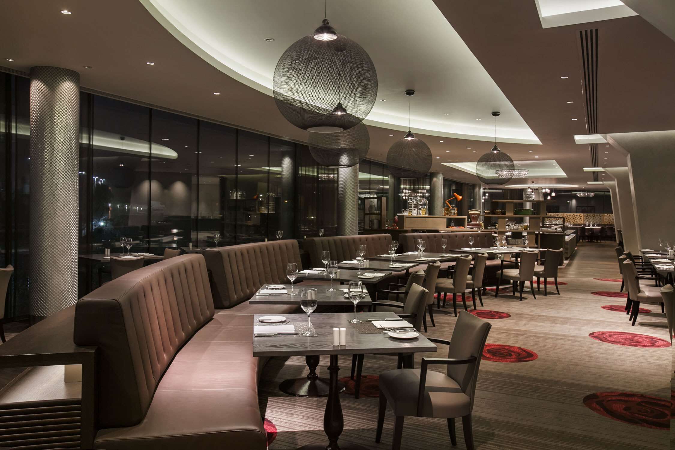 A modern restaurant with high tables, cushioned seating, and pendant lighting.