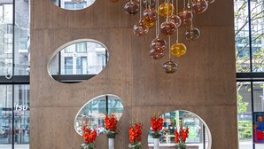 Una hall dal design moderno, con ornamenti sferici in vetro sospesi, una reception e ampie finestre che offrono vista sulla città.