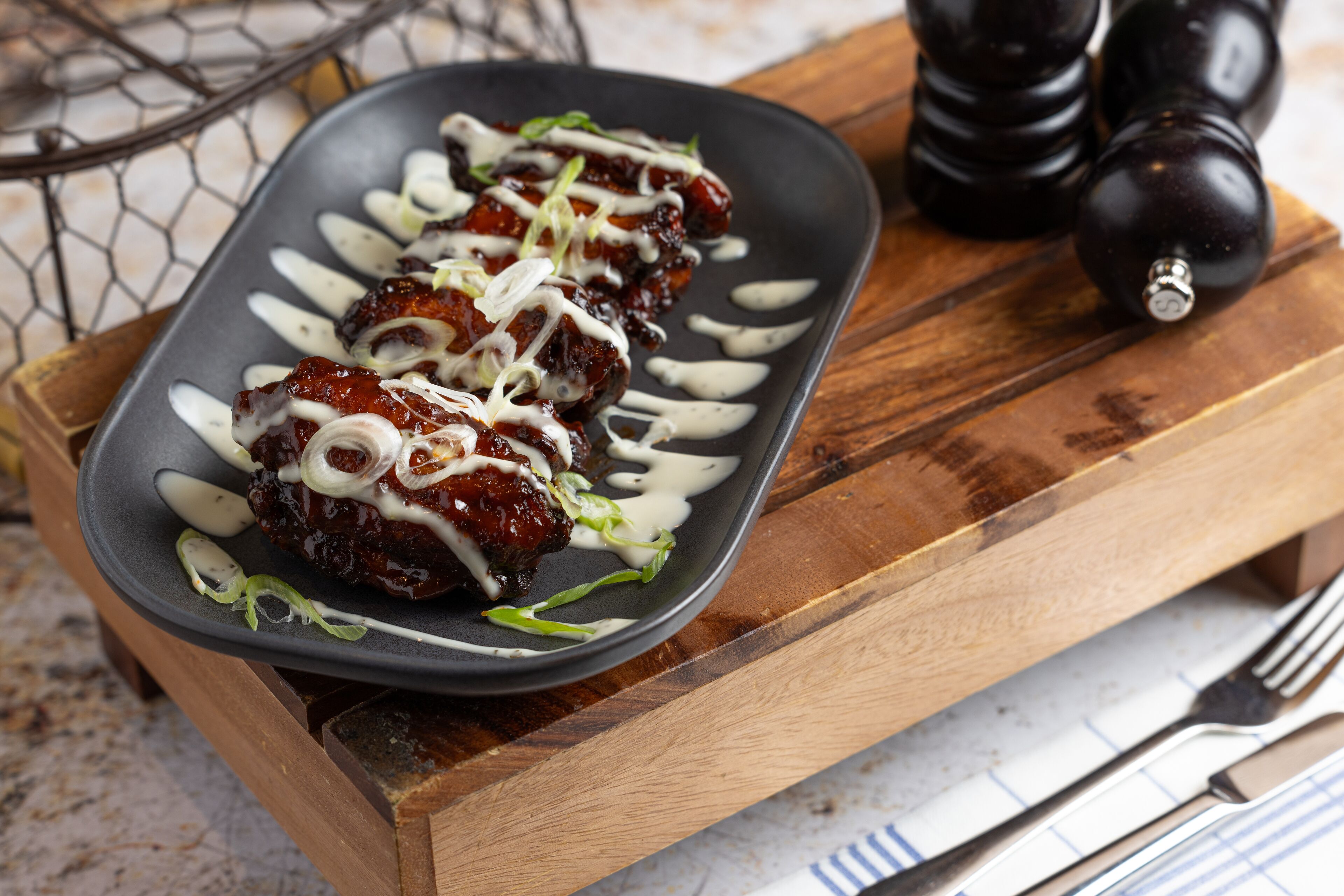 A plate of food with a dark plate on a wooden board.