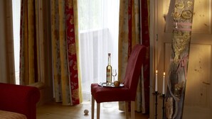 Una habitación con una silla roja, una mesa con una botella y un vaso, y una pared decorativa con un cartel.