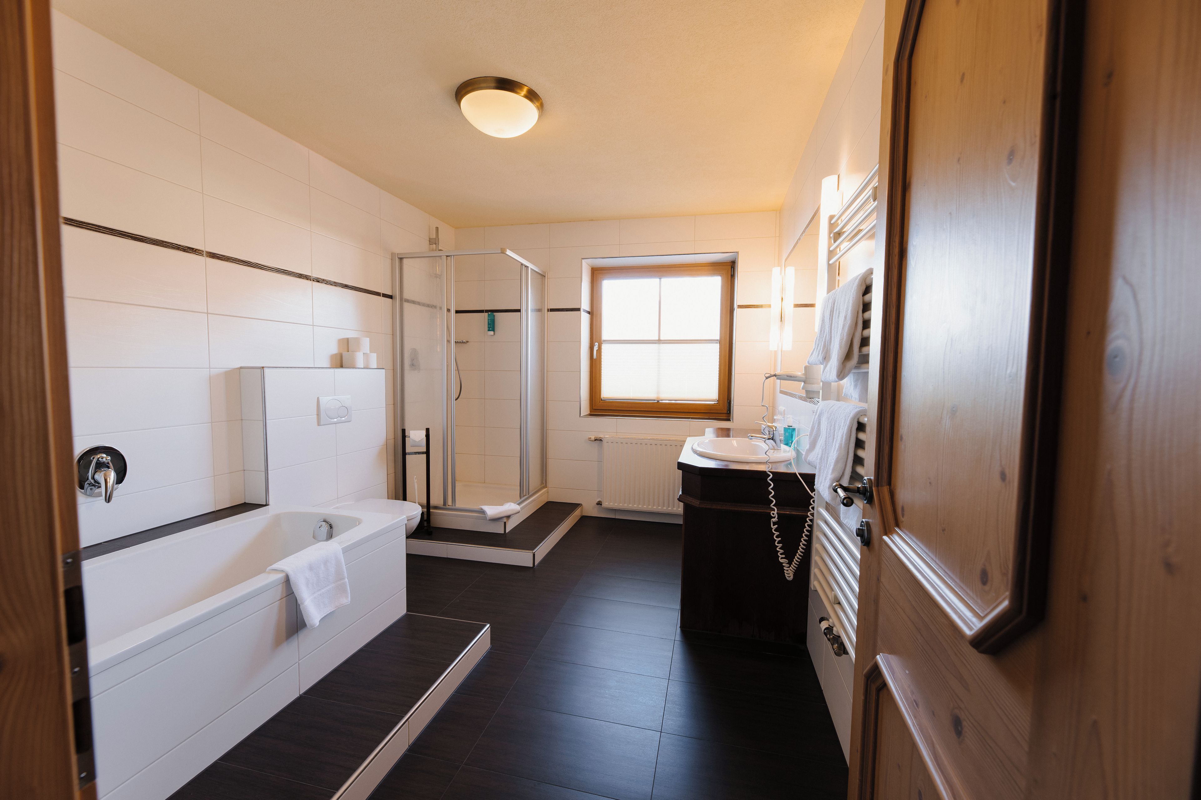 Ein modernes Badezimmer mit Badewanne, Dusche und Waschtisch.