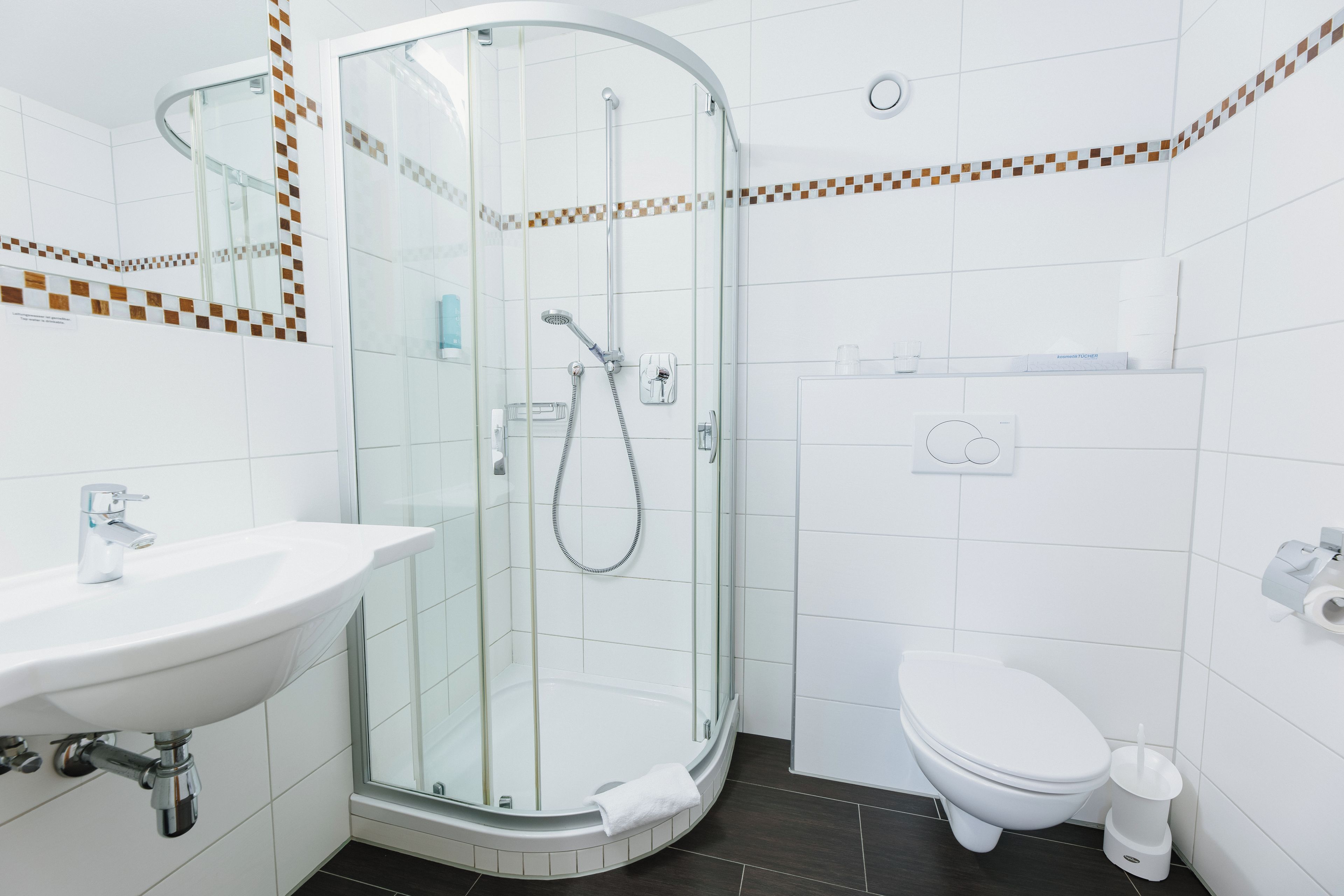 A modern bathroom with a glass-enclosed shower, a white sink, and a toilet.