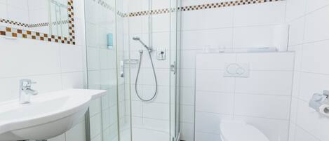 A modern bathroom with a glass-enclosed shower, a white sink, and a toilet.