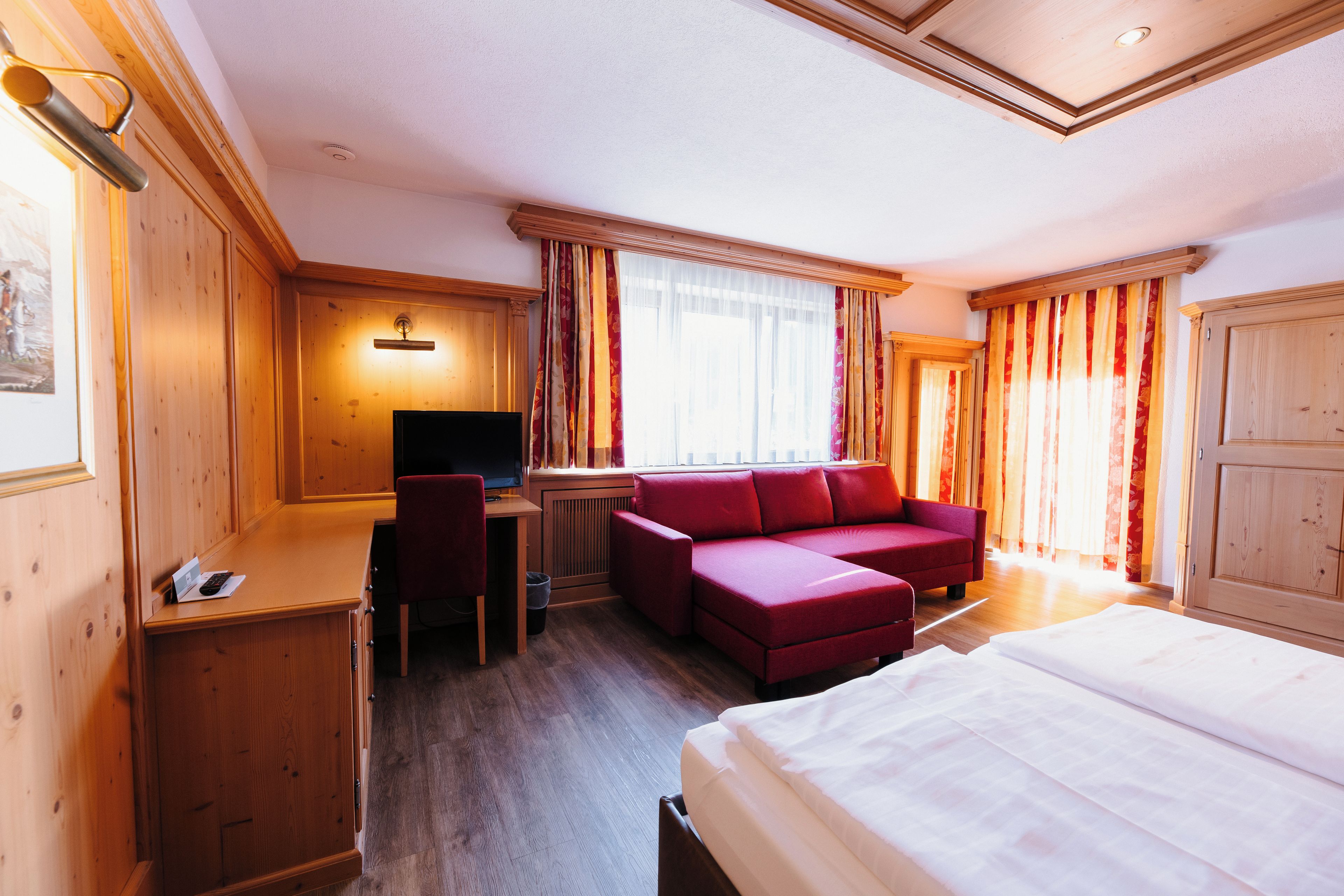 Una habitación de hotel con cama, escritorio, silla, sofá y televisor.