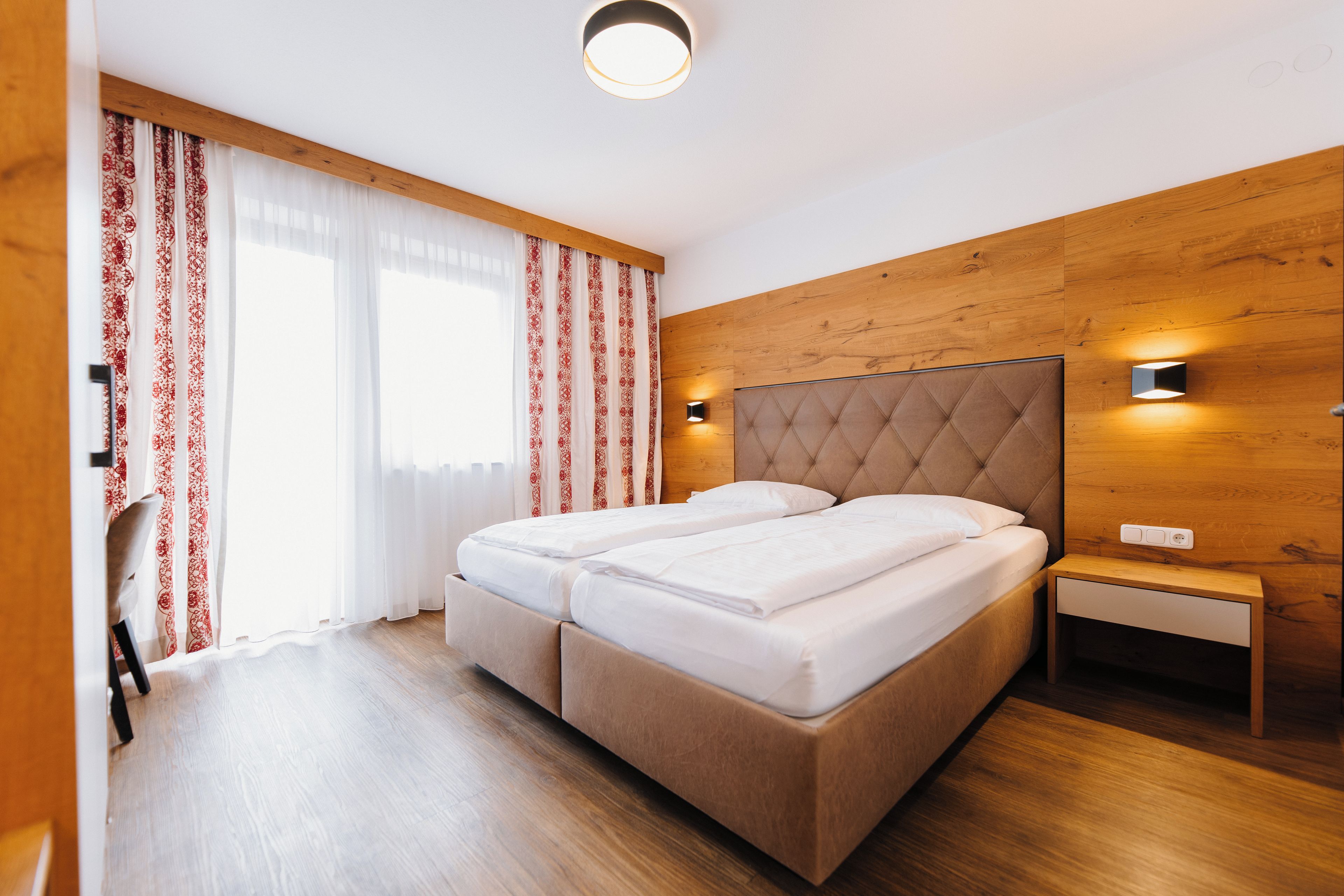 A double bed with a wooden headboard, a bedside table, and a nightstand.