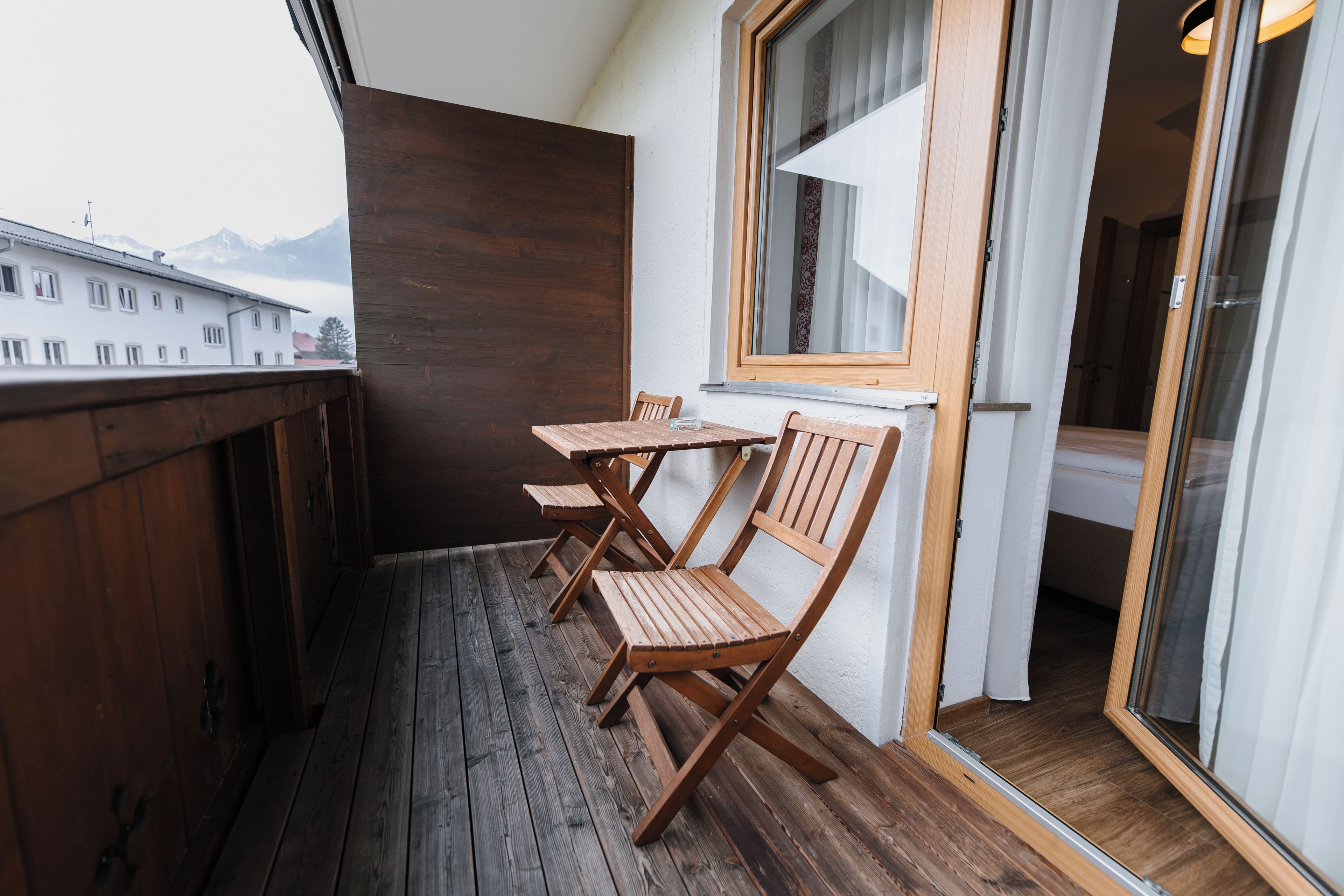 A balcony with wooden flooring, a table, and two chairs.