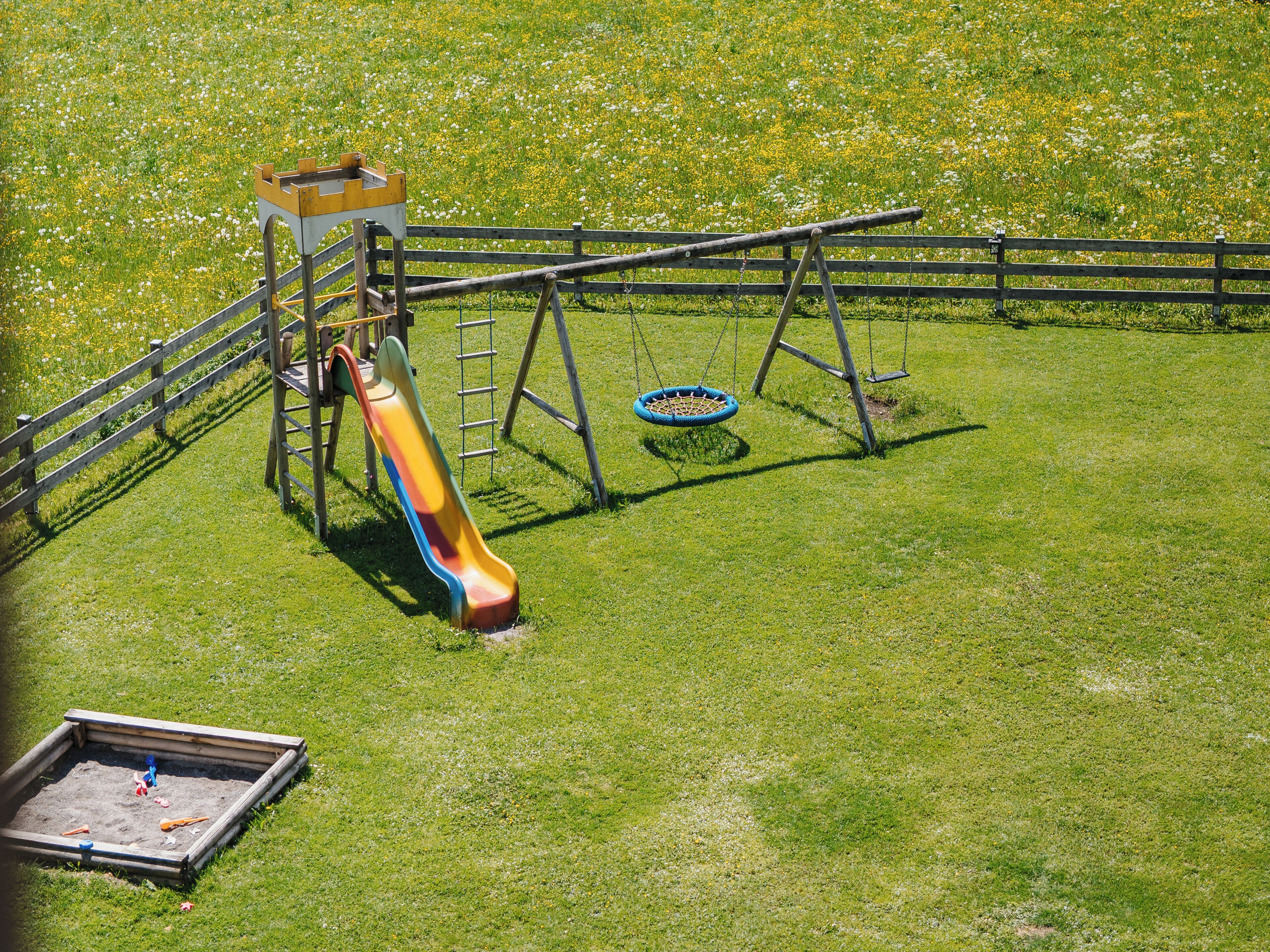 A playground with a slide, swing set, and sandpit.