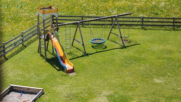 A playground with a slide, swing set, and sandpit.