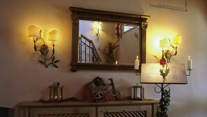 A dimly lit room with a wooden cabinet, a mirror, and wall-mounted sconces. - Alpenhotel Ernberg (Breitenwang)