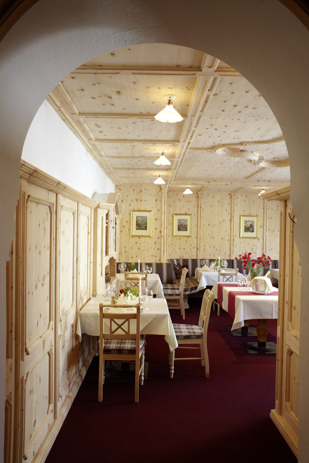 A dining area with wooden paneling, tables set for dining, and framed artwork on the walls.