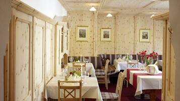 A dining area with wooden paneling, tables set for dining, and framed artwork on the walls.