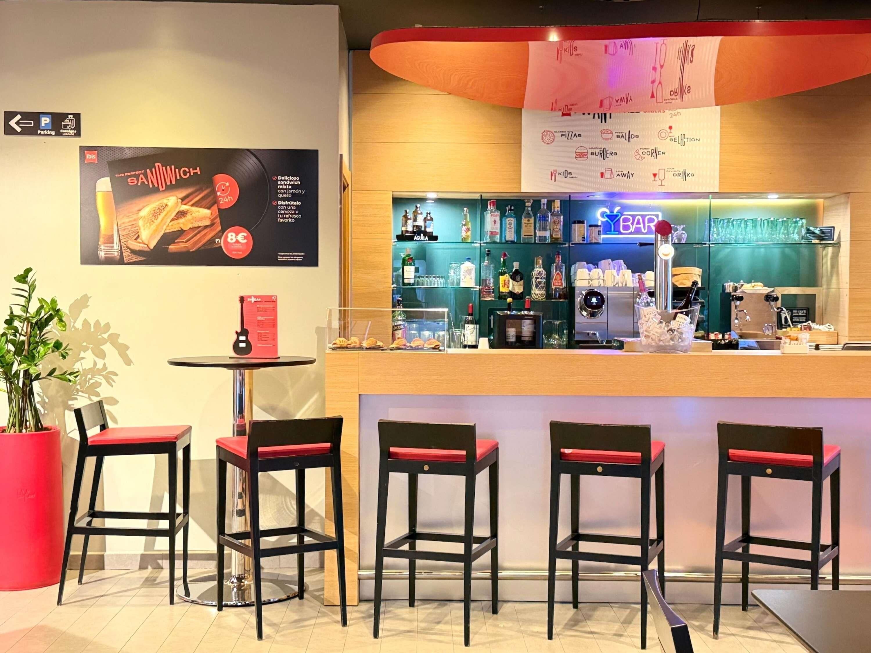 Zona de bar con un tablero de menú, asientos y una barra con diferentes botellas.