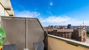 A balcony with a view of a cityscape, including a historic building with flags.