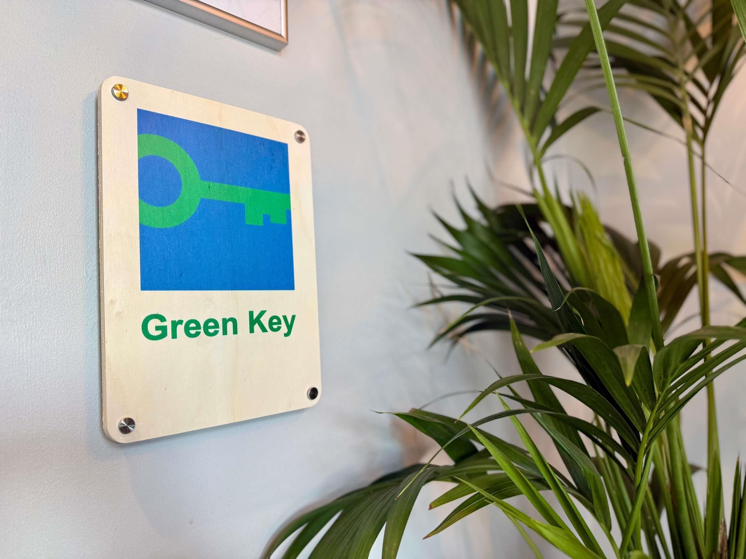 Een bord met een sleutelafbeelding en de tekst 'Green Key' aan een muur.