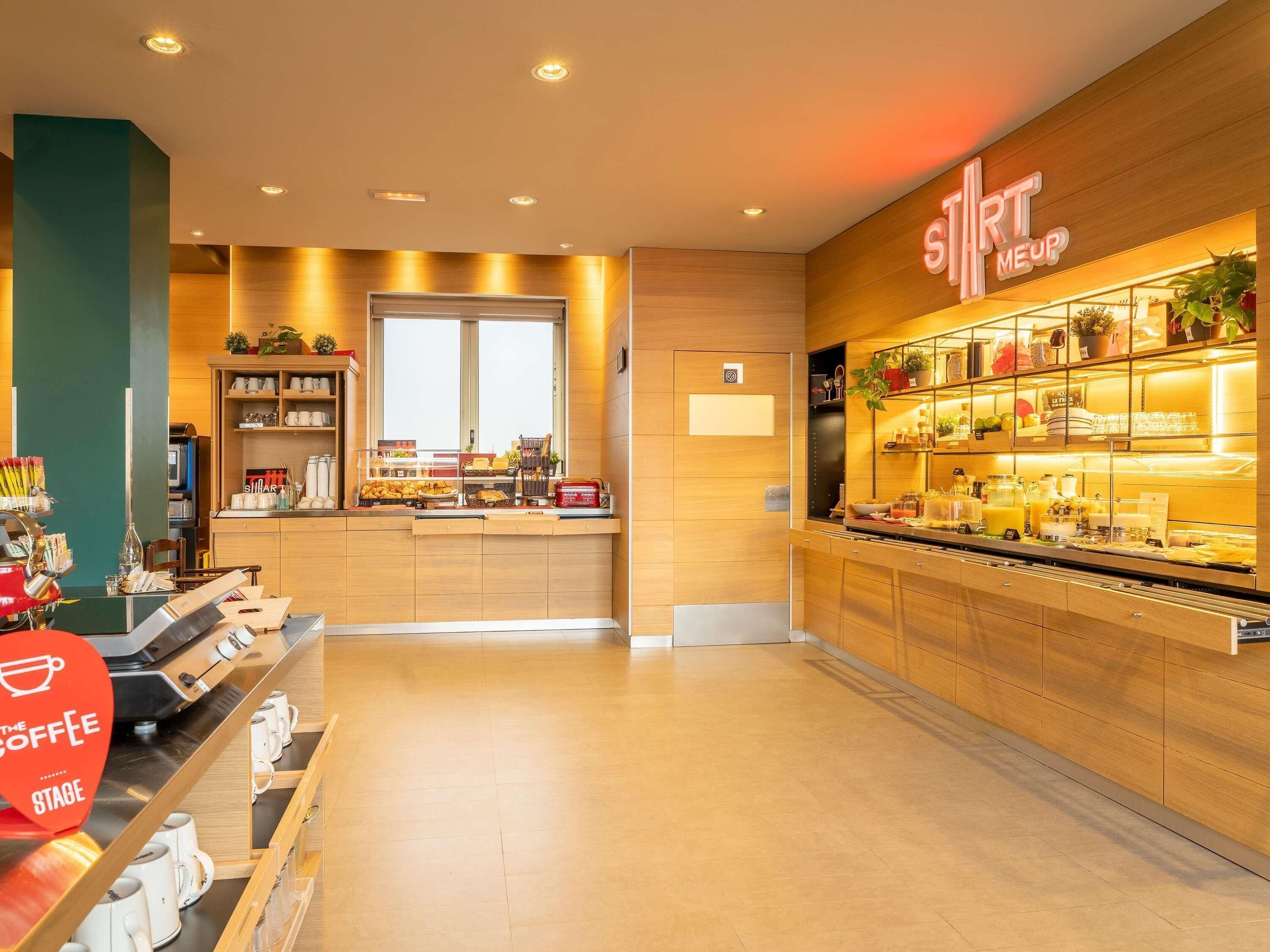 L’intérieur d’un café moderne, avec un espace dédié au café, des étagères remplies de pâtisseries et un panneau indiquant « sIRT MEUP ».