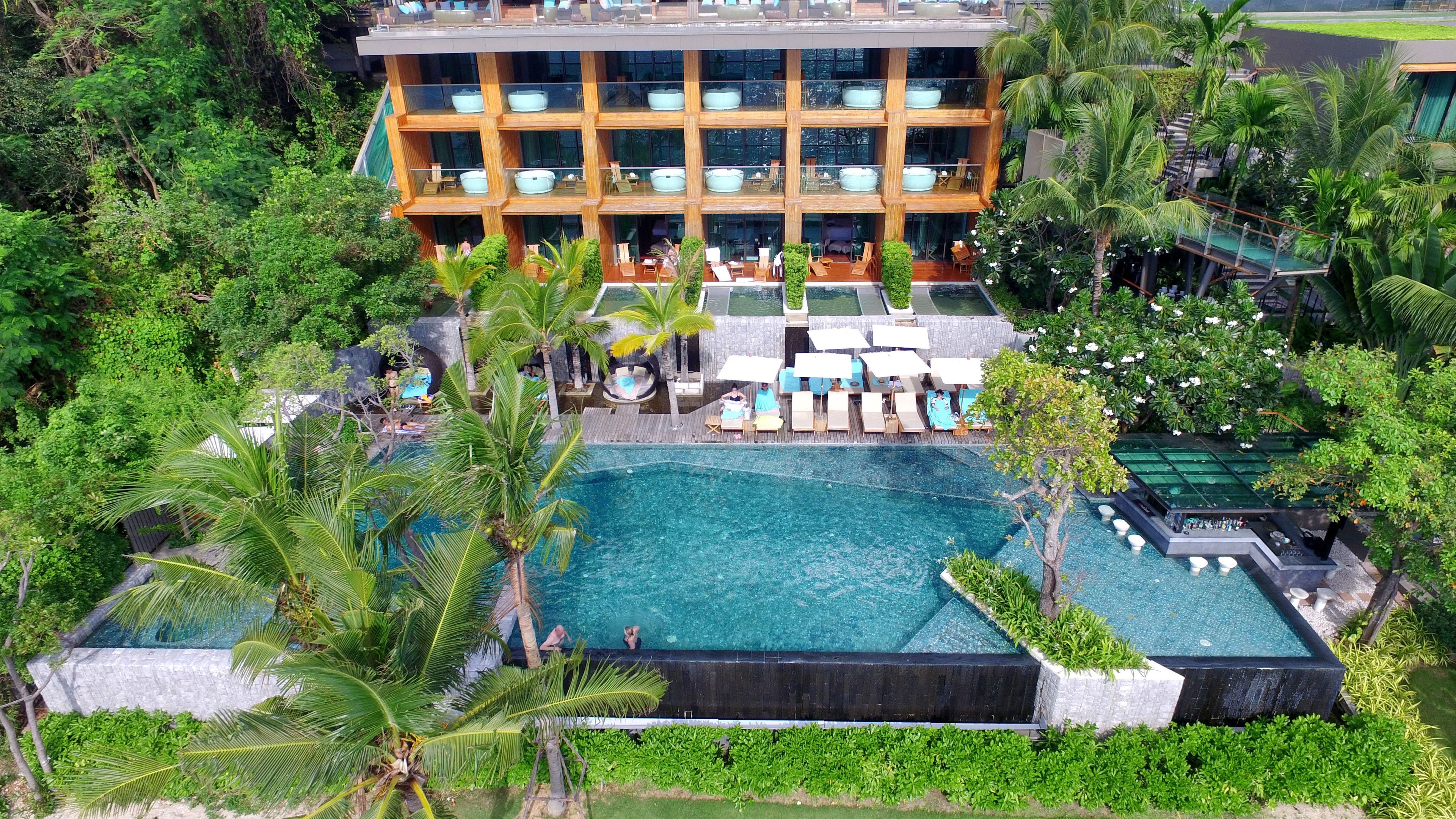 A resort with a large pool, multiple lounge areas, and a building with balconies.