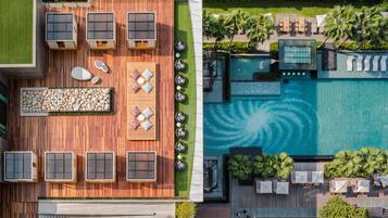 An aerial view of a rooftop with a swimming pool, outdoor seating, and a pebble garden.