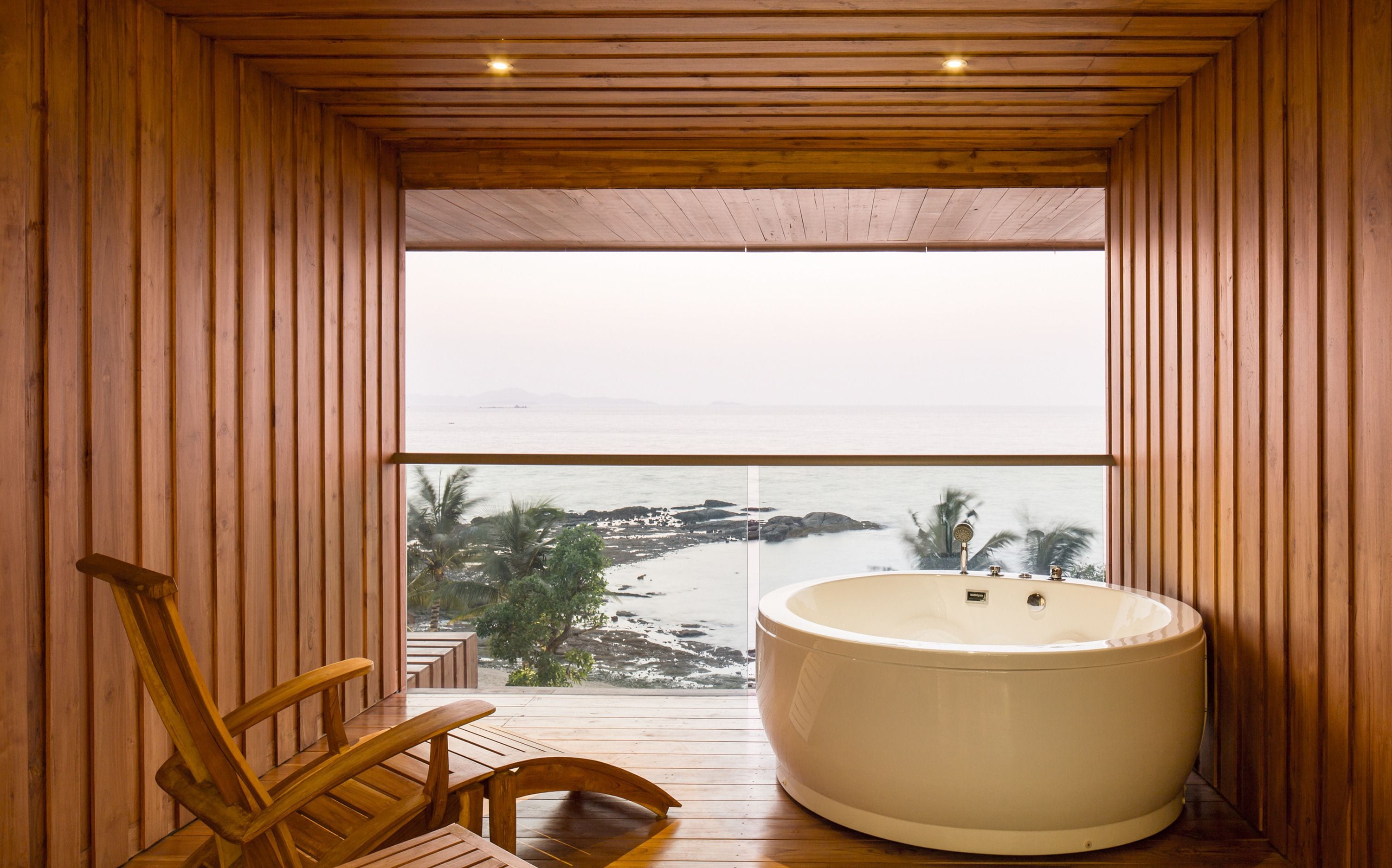 Una cabaña de madera con una bañera grande y vista al océano.