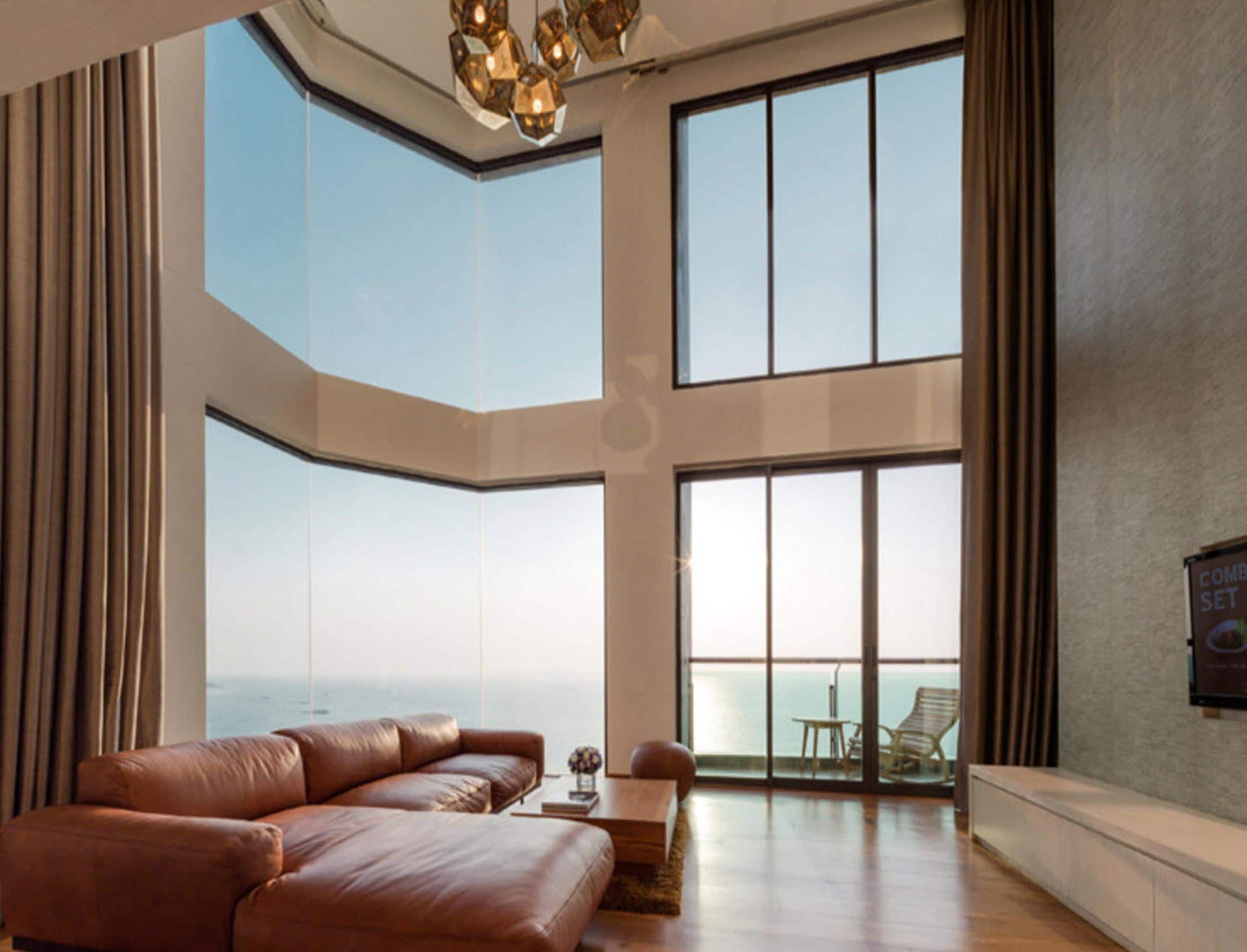 A spacious living area with a large window overlooking the sea, a leather sofa, and a wooden coffee table.
