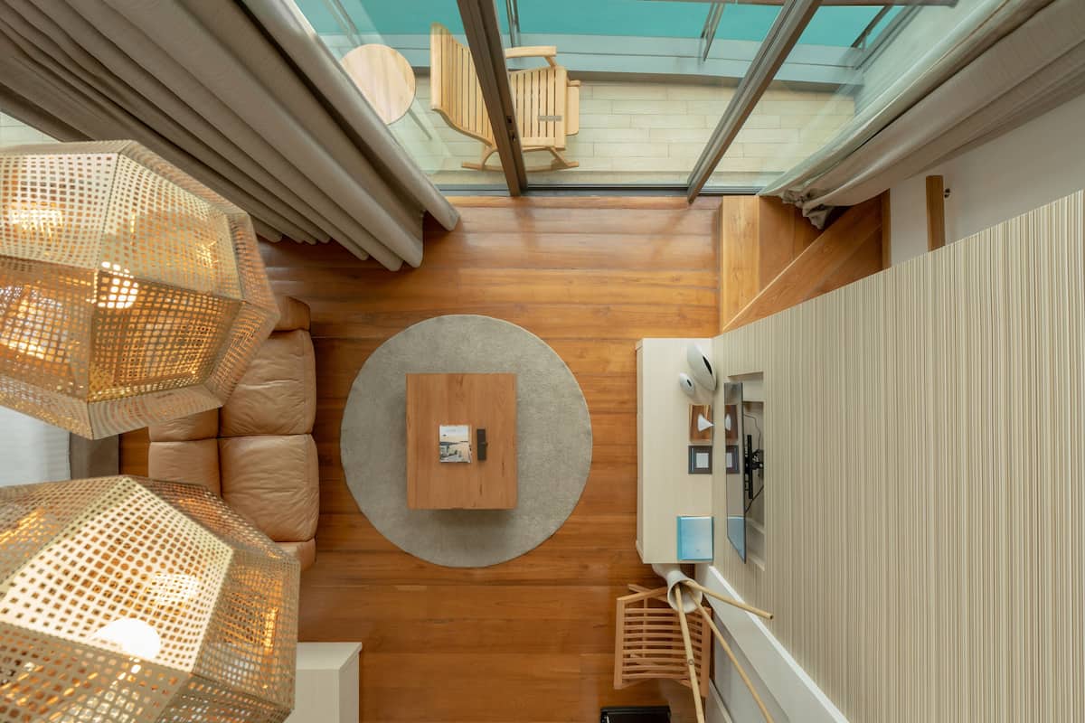 A modern interior with a wooden floor, a round table, and a glass ceiling overlooking a balcony.