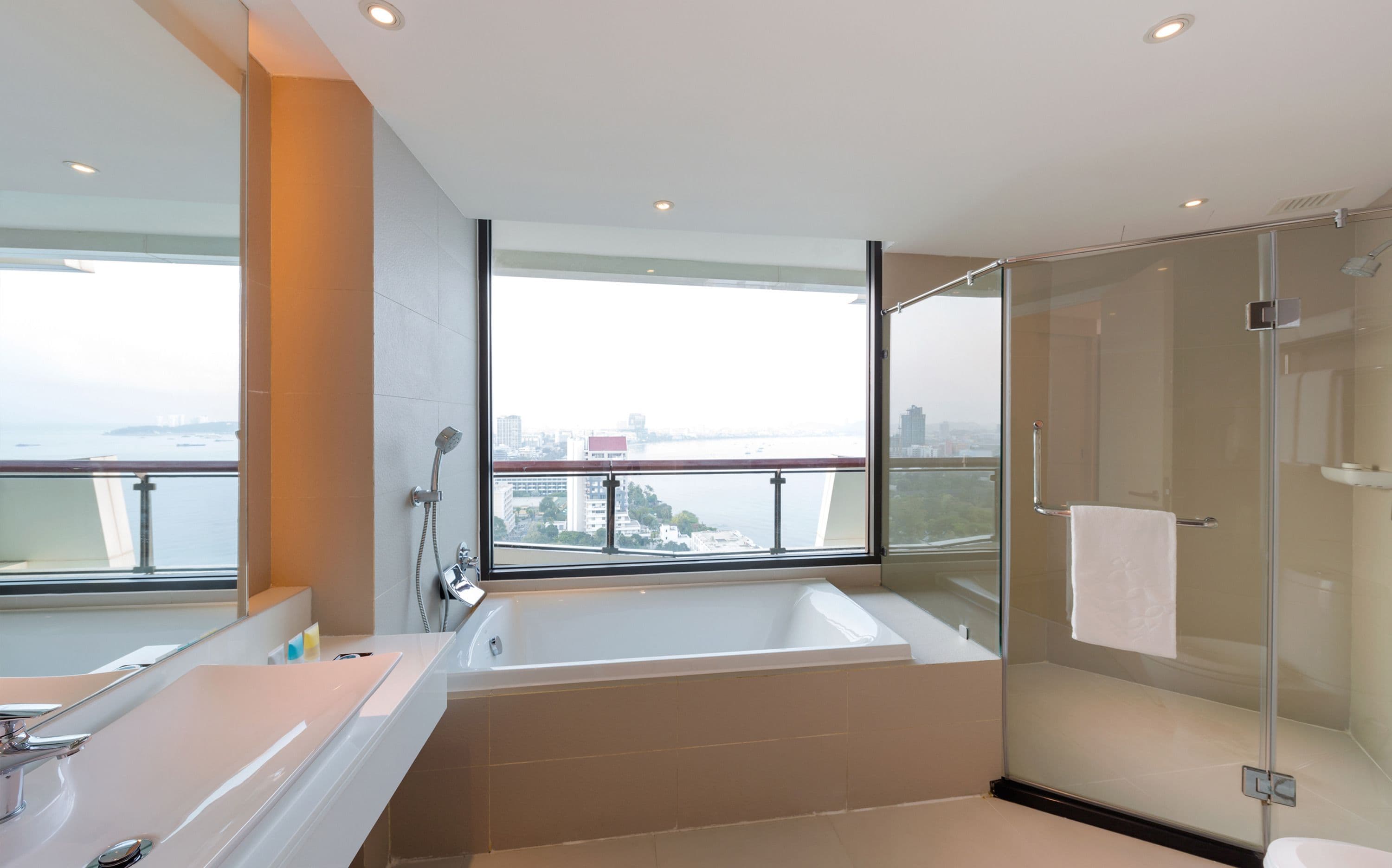 Un baño moderno con una bañera grande, una ducha con mampara de vidrio y vistas a la ciudad.