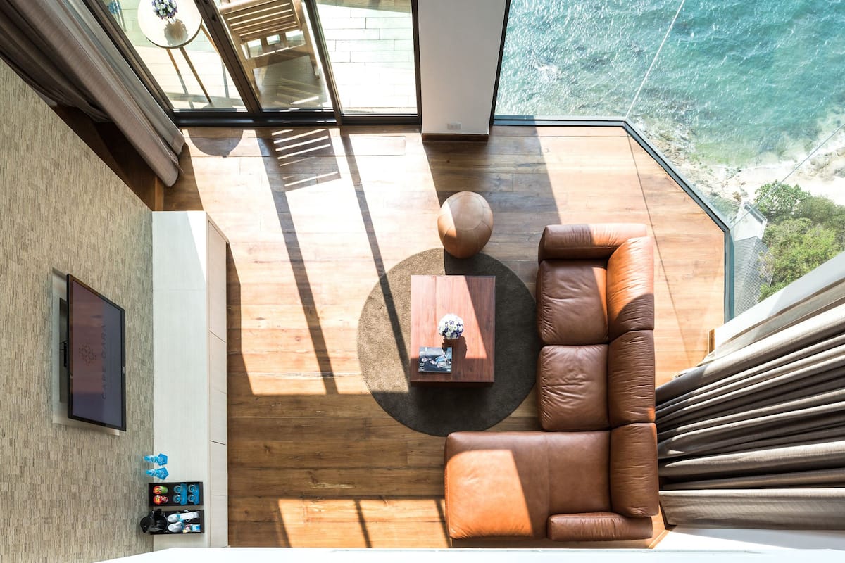 A modern living room with a leather sofa, a wooden coffee table, and a view of the ocean.