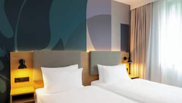 A hotel room with two beds, a nightstand with a lamp, and a wall with abstract art.