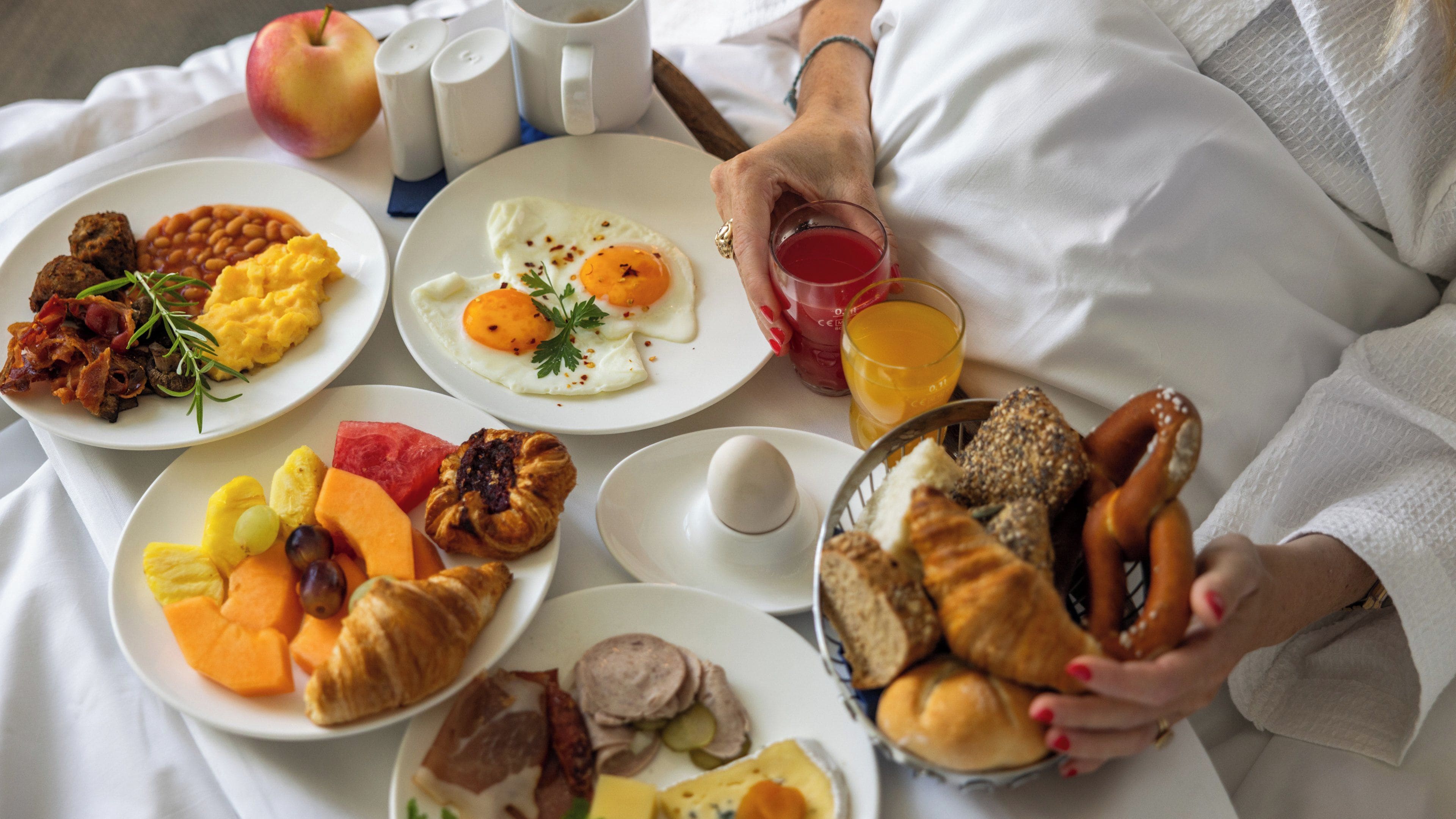 A breakfast spread with various dishes and a glass of orange juice.