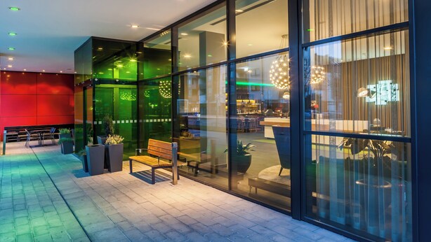 Un interior moderno con zona de estar, ventanas amplias y un bar visible a través del vidrio.