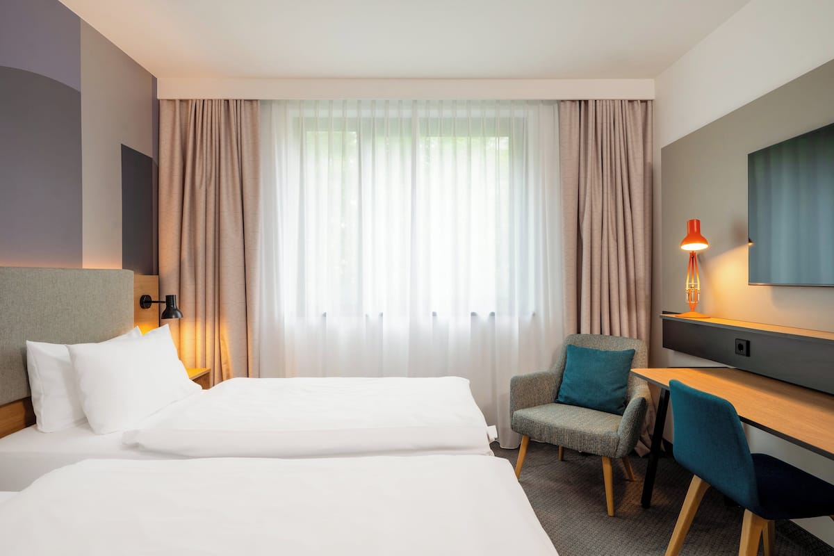 A hotel room with two beds, a desk, and a chair.