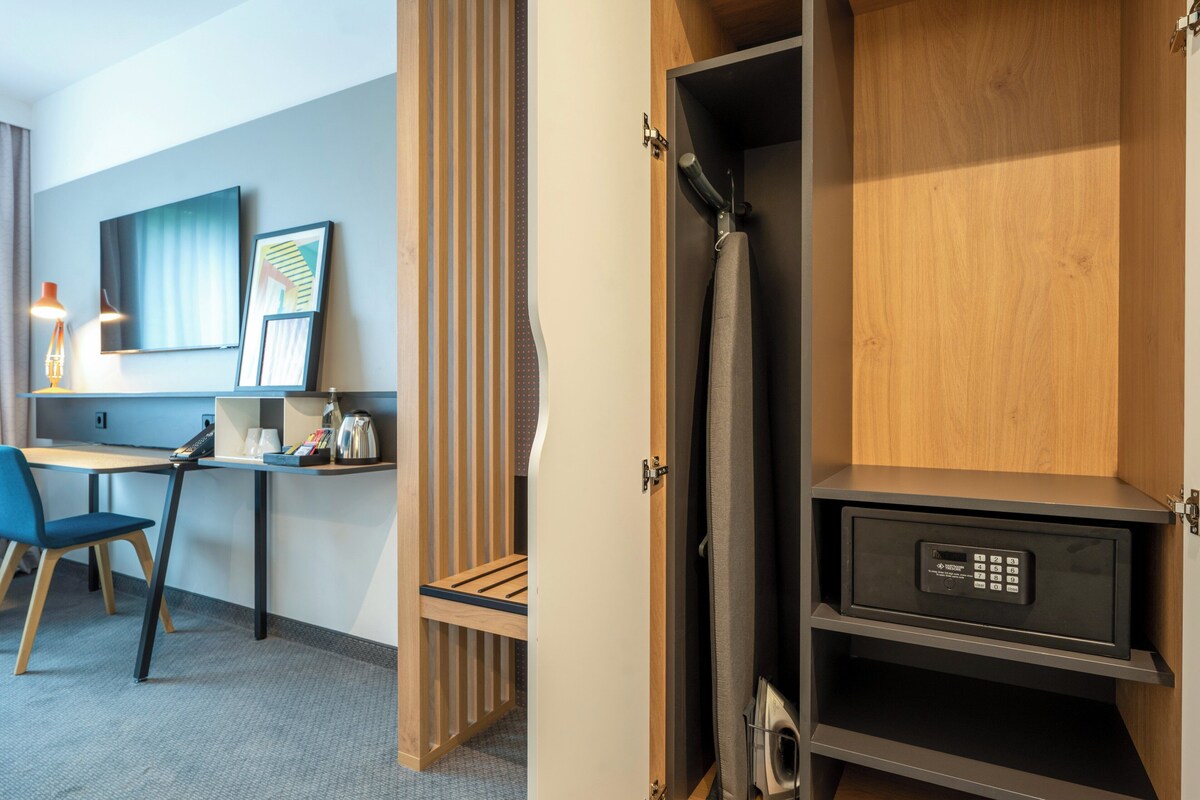 Habitación de hotel con escritorio, silla y caja fuerte.