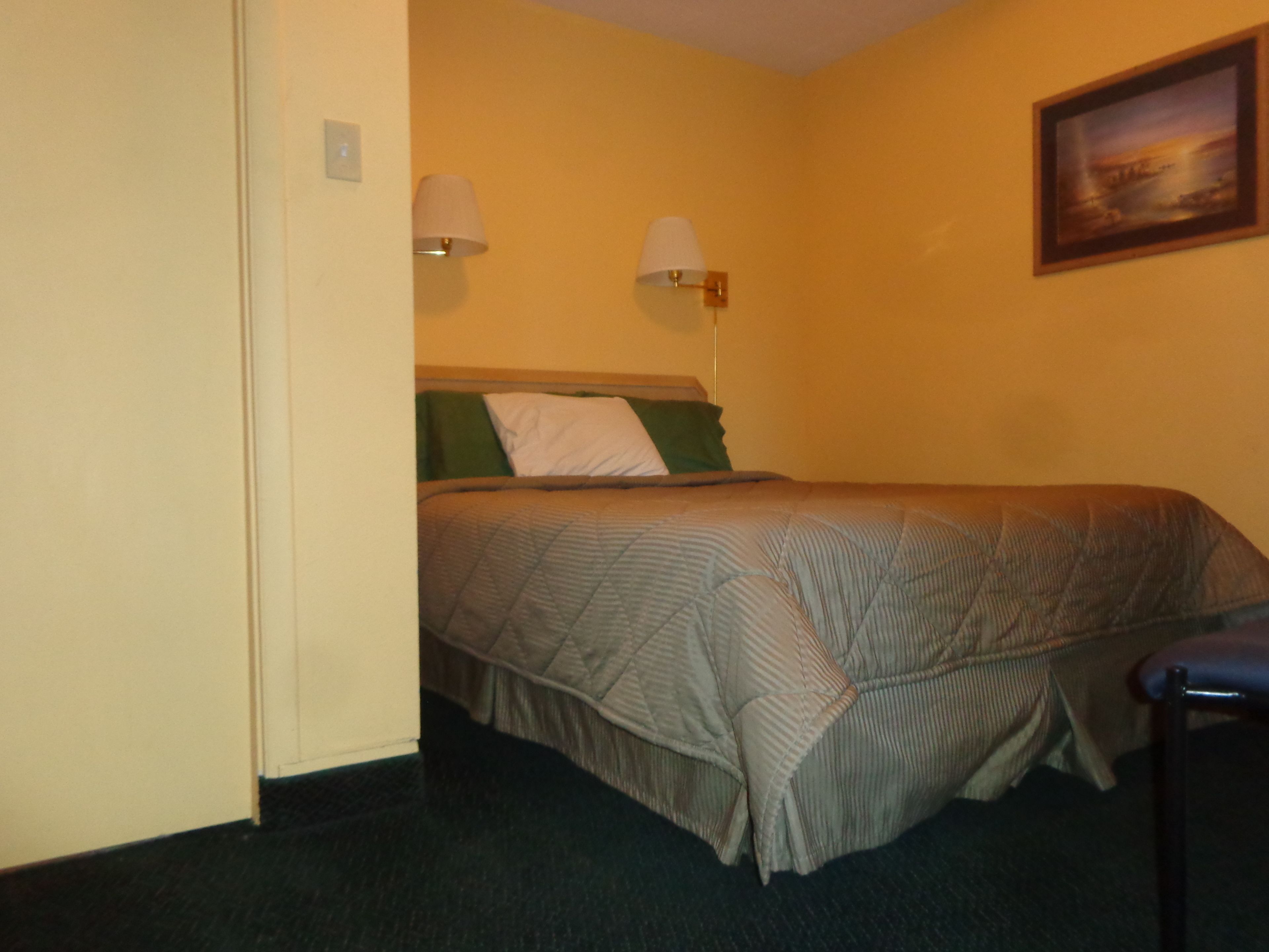 Una habitación de hotel con una cama, dos lámparas de pared y un cuadro en la pared.