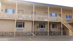 Ein zweistöckiges Motel mit Balkonen, einer Stein-Fassade und einem Motorrad davor.