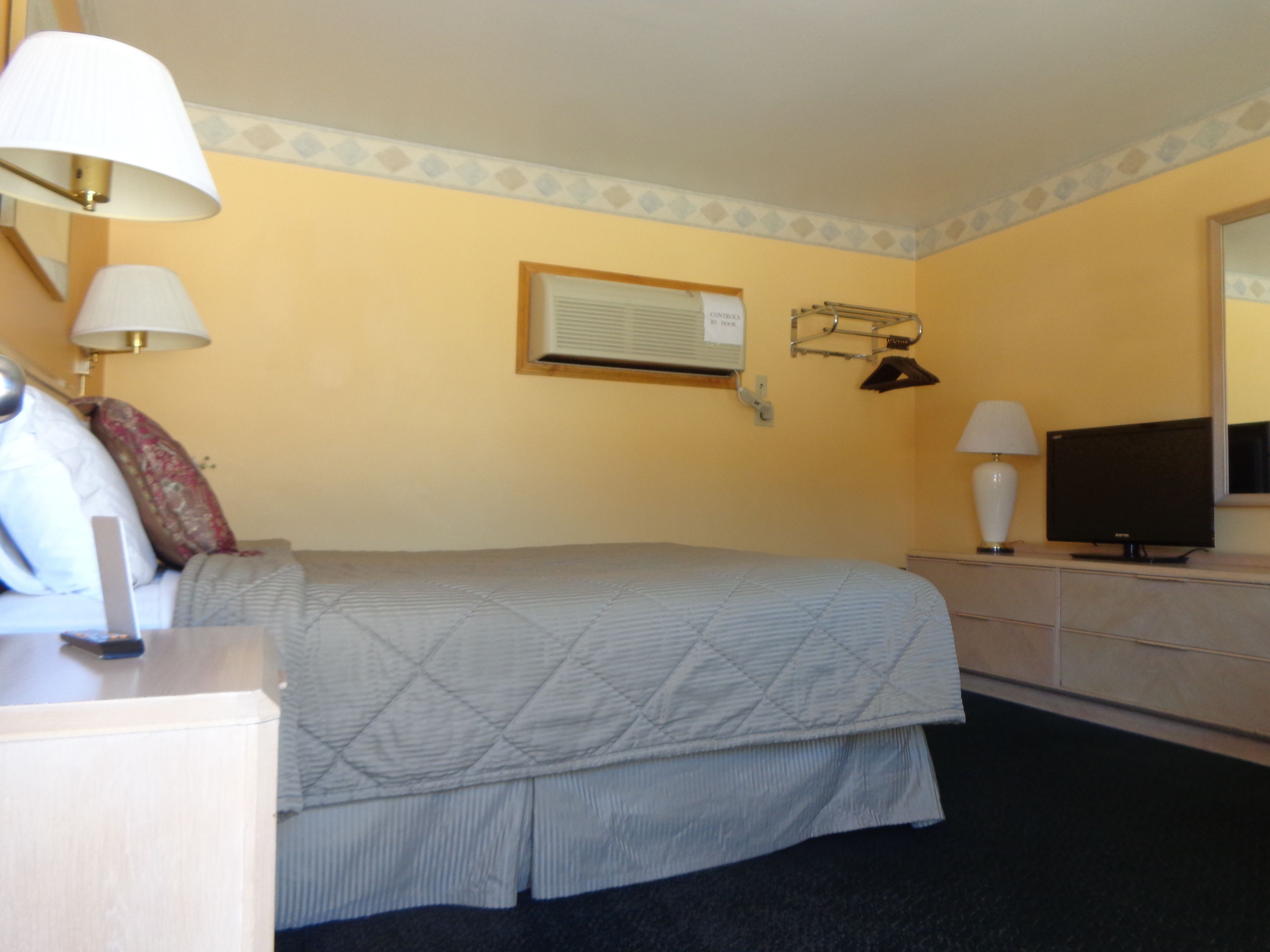 A hotel room with a bed, bedside lamps, a television, a dresser, and a mirror.