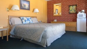 Ein Hotelzimmer mit Bett, Schreibtisch, Mikrowelle und Backsteinwand.