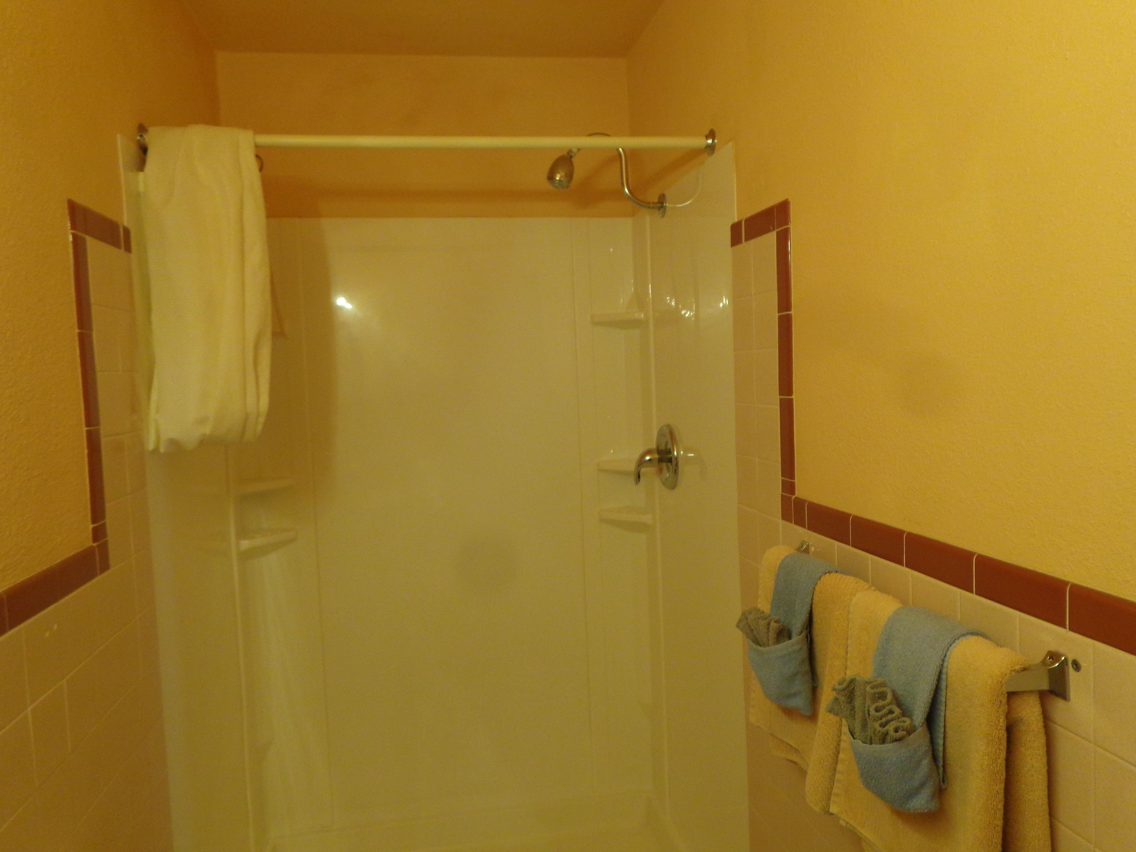 A bathroom with a glass shower door, a towel rack with multiple towels, and tiled walls.