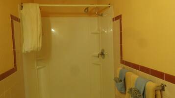 A bathroom with a glass shower door, a towel rack with multiple towels, and tiled walls.