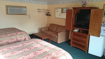 Una habitación compacta con dos camas, un sofá, televisión y una pequeña kitchenette.
