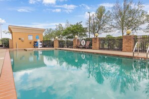 A swimming pool with lounge chairs and a building in the background.