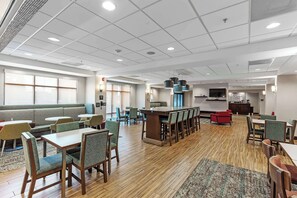 A spacious hotel lobby with a reception desk, seating areas, and a large window.