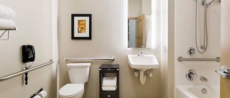 A bathroom with a toilet, sink, and bathtub. There is a framed picture on the wall, a telephone, and a towel rack.