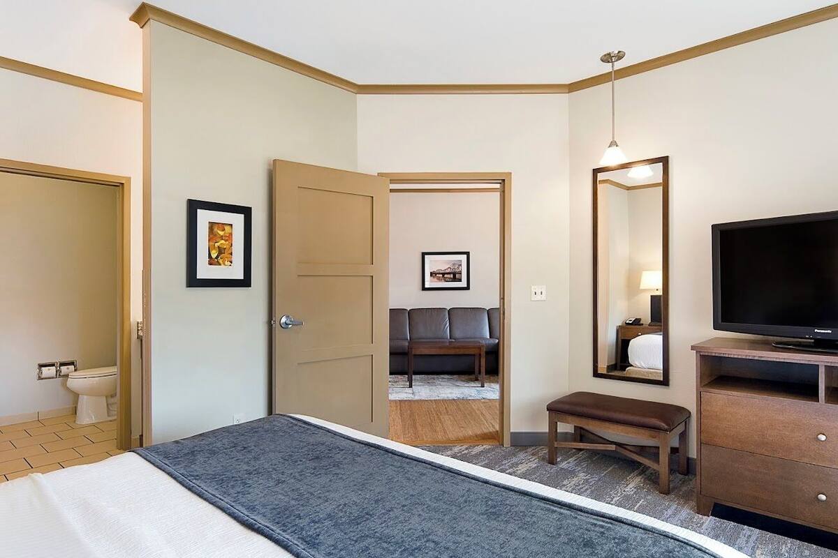 Ein Hotelzimmer mit einem Bett, einem Fernseher, einem Schreibtisch, einem Sessel und einem Schlafsofa.