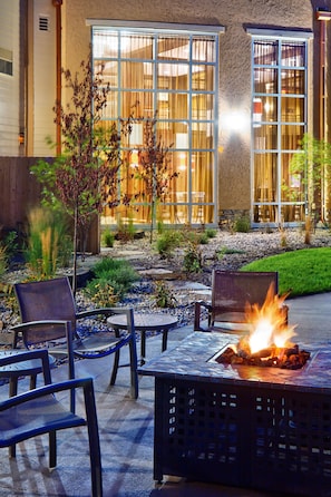 An outdoor seating area with a fire feature, surrounded by chairs and a small table. - Clubhouse Hotel & Suites Pierre (Pierre)