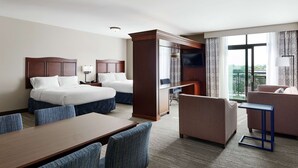 Ein Hotelzimmer mit zwei Betten, einem Schreibtisch, einem Stuhl, einer Couch und einem Fernseher.